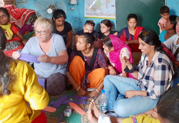 Terryl demonstrating sewing sanitary pads in slum in Delhi